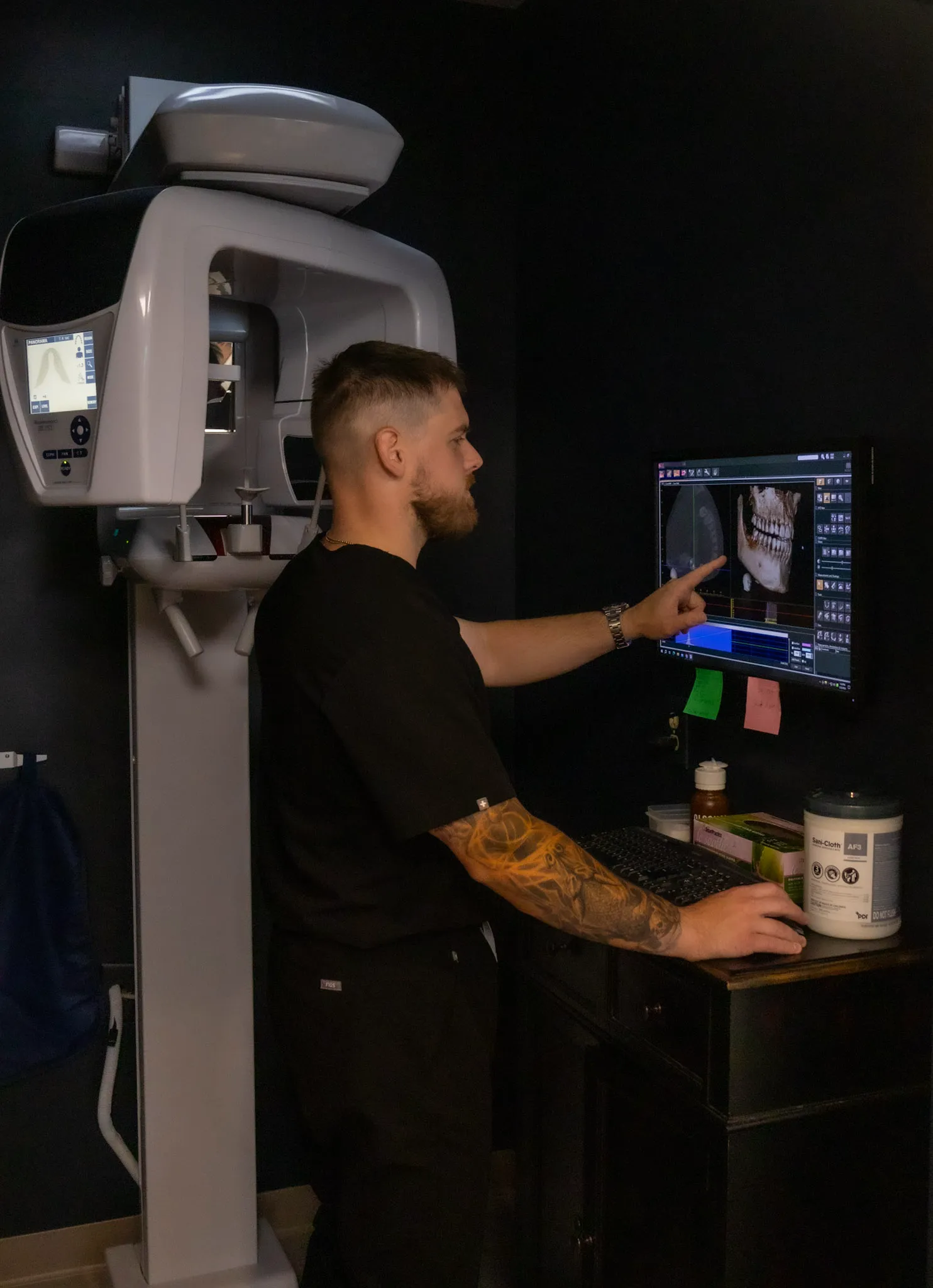 A team member reviewing dental imaging beside a panoramic x-ray machine